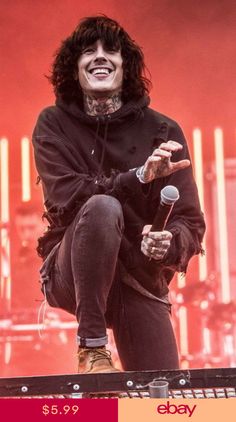 a man with long hair and piercings on his face is sitting on a stage