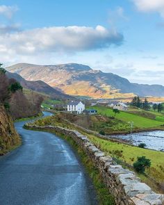 the road is empty and there are mountains in the distance with houses on either side