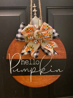 a door hanger that says hello pumpkin hanging on the front door with an orange and black bow