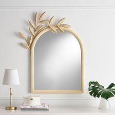 a mirror sitting on top of a white table next to a lamp and a potted plant