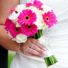 a bride holding a bouquet of pink and white flowers