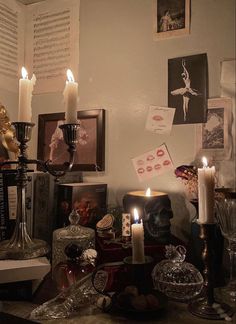 a table with candles, pictures and other items on it in front of a wall