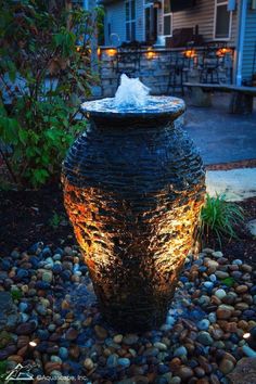 a water fountain in the middle of a garden with rocks around it and lights on