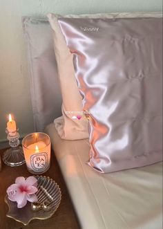 two candles are sitting on a table next to a pillow