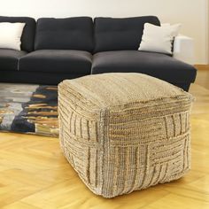 a living room with a couch, ottoman and rug on the wooden floor in front of it