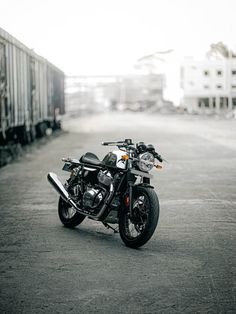 a motorcycle parked on the side of a road next to a train track with buildings in the background