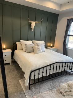 a bed room with a neatly made bed and a cow skull mounted on the wall