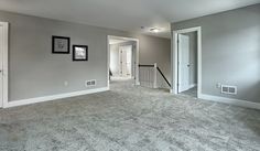 an empty living room with gray walls and carpet