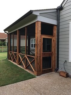 a house with a screened porch in front of it and grass around the back yard