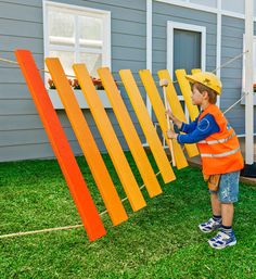 a little boy that is standing in the grass with some wooden boards on his back