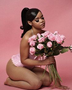 a woman kneeling on the ground holding a bouquet of roses