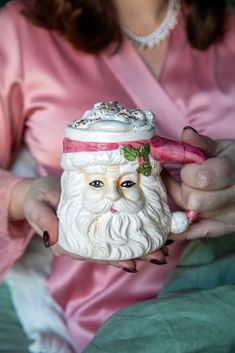 a close up of a person holding a cup with a santa clause on it's head