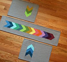 two pieces of fabric with arrows on them sitting on top of a wooden floor next to each other