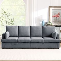 a living room scene with focus on the grey couch and white carpeted flooring