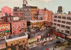 there are many buildings and cars on the model train set that is in front of them