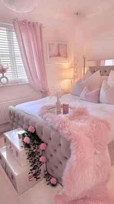 a bedroom decorated in white and pink with lots of fur on the bed, pillows and rugs