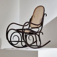 a wooden rocking chair sitting on top of a white floor next to a wall in a room