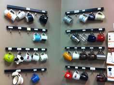 coffee cups and mugs are hanging on the wall next to each other in a display