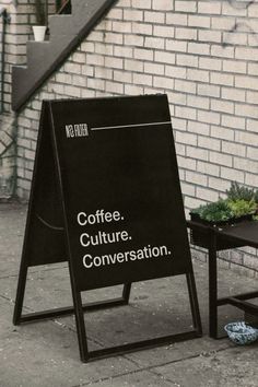 a sign sitting on the side of a building next to a table with a plant in it