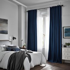 a bedroom with white walls and blue curtains