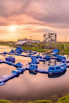 an amusement park with water slides and inflatable boats on the lake at sunset