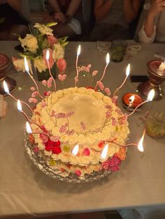 a birthday cake with lit candles sitting on a table