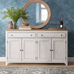 a white dresser with a mirror and bottles on it in front of a blue wall