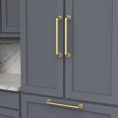 a kitchen with gray cabinets and marble counter tops, gold handles on the door knobs