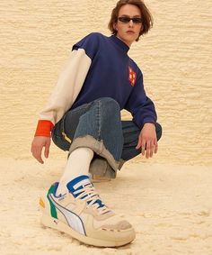 a person sitting on the ground with their foot up in the sand and wearing sunglasses