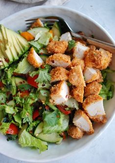 a salad in a bowl with chicken and avocado on the side is ready to be eaten