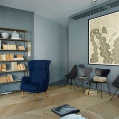 a living room filled with furniture and bookshelves next to a painting on the wall