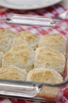 a casserole dish filled with biscuits on a red and white checkered tablecloth