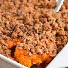 a casserole dish filled with sweet potatoes and crumbled pecans on top