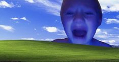 a man with his mouth wide open in front of a green field and blue sky