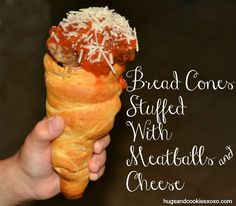 a hand holding an ice cream cone filled with meatballs and cheesy bread