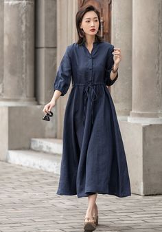 "This Navy blue linen shirt dress is the pinnacle of staple style, The 1950s vintage dress crafted with 100% linen, featuring a v neckline and button front, three quarter sleeves, and a drawstring waist. This simple and comfortable midi dress oozes easy going style as well as comfort. DETAILS * 50% linen blend, 50% cotton, medium weight linen, organic linen dress * Shirt dress style with front buttons * Two side seam pockets * Drawstring waist, can adjust, perfect for everyone (Including pregnan Blue Mid-length Buttoned Dress, Elegant Button-up Linen Dress, Casual Blue Button-up Midi Dress, Feminine Midi-length Shirt Dress With Buttons, Casual Linen Shirt, Shirt Dress With Pockets, Blue Linen Button-up Dresses, Chiffon White Dress, Blue Linen Dress