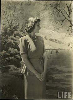 an old black and white photo of a woman standing in front of a wall painting