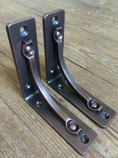 two metal brackets on top of a wooden table