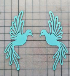 two metal peacocks sitting on top of a tile floor next to each other with their wings spread out