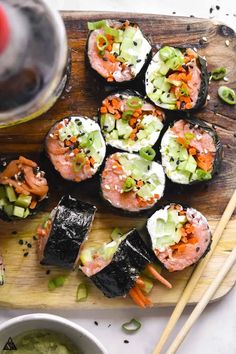 sushi on a wooden cutting board with chopsticks and a glass of wine