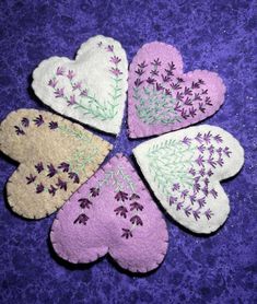 four heart shaped felt appliques sitting on top of a purple surface