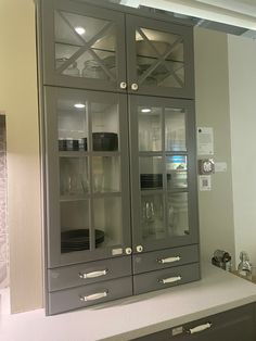 a kitchen cabinet with glass doors and drawers