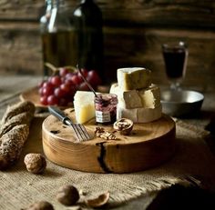 cheese and nuts on a wooden board with wine in the background