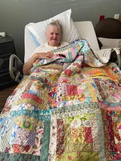 a woman laying in a hospital bed with a quilt on top of her and smiling at the camera