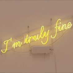 a neon sign that says i'm finally fine hanging from the side of a wall