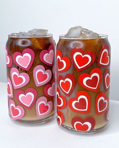 two jars with hearts painted on them sitting next to each other, one filled with ice