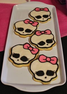 decorated sugar cookies with bows and skulls on a white platter, ready to be eaten