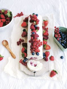 there is a cake with berries on it and other fruit around it, including raspberries