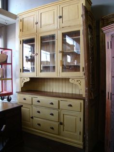 an old china cabinet with glass doors and drawers in a room filled with other furniture