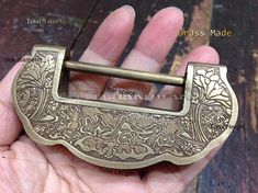 a hand holding a brass colored belt buckle